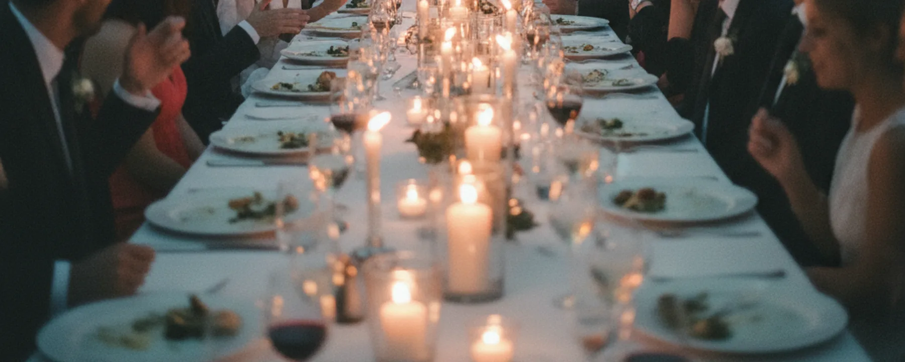 Lange Tafel mit Gästen beim Hochzeitsessen in der Abenddämmerung